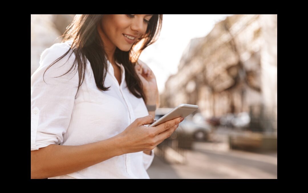 a woman with long brown hair outside looks at her phone