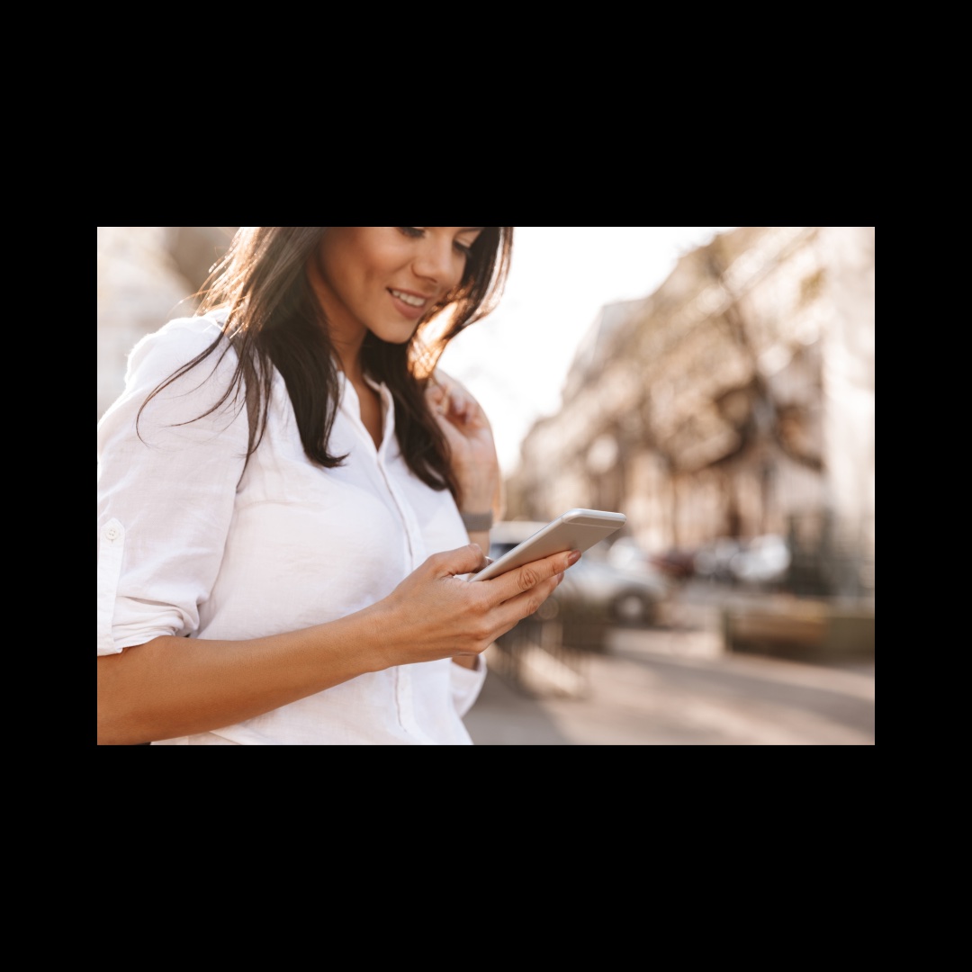 a woman with long brown hair outside looks at her phone